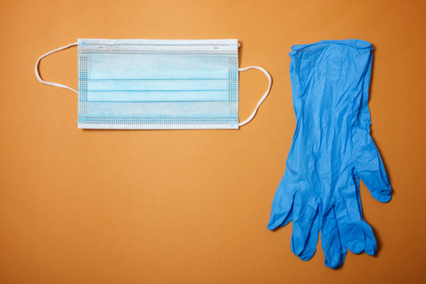 istock Surgical mask and gloves on an orange table. 1240048636