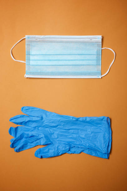 istock Surgical mask and gloves on an orange table. 1240048638