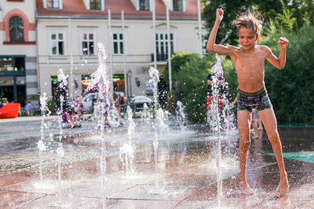 istock Child playing with water in park fountain 1240097295