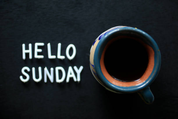 istock Hello Sunday greeting with a cup of black coffee on dark table background. 1240099449