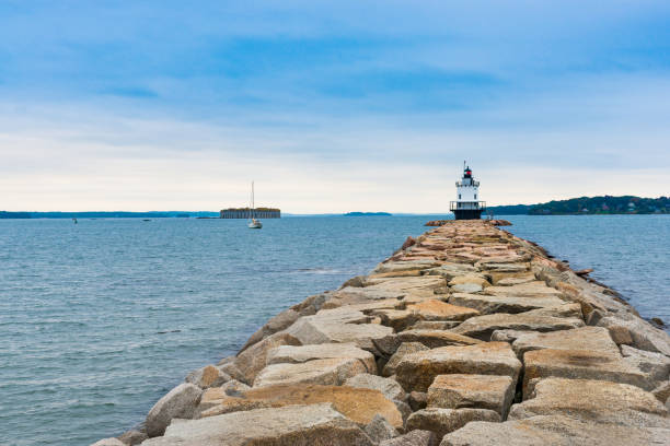 Portland Maine, Bug Lighthouse. Portland Maine, Bug Lighthouse in bay with rock path and breawater leading to beacon. casco bay stock pictures, royalty-free photos & images