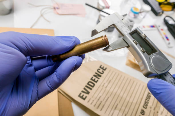 la polizia esperta misura il calibro del proiettile in laboratorio balistico, immagine concettuale - risultati di prova foto e immagini stock