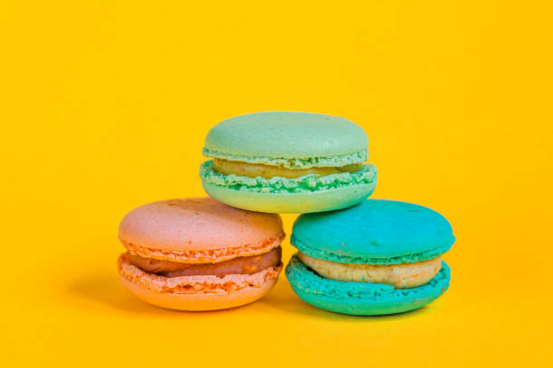 Sweet almond colorful unicorn pink blue yellow green macaron or macaroon dessert cake isolated on trendy yellow modern fashion background. French sweet cookie. Minimal food bakery concept. Copy space almendra dulce colorido unicornio rosa azul amarillo verde verde o macarrones pastel de postre aislado en el fondo de moda moderna amarillo de moda de moda. galleta dulce francesa. concepto mínimo de panadería de alimentos copiar espacio