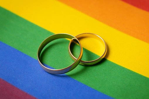 concepto de matrimonio entre personas del mismo sexo - dos anillos de boda en la bandera arco iris lgbt photo
