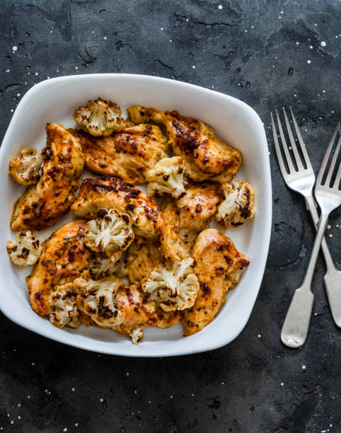 istock Roasted chicken breast fillets with cauliflower cabbage on a dark background, top view. Delicious lunch, tapas, appetizers 1240201793
