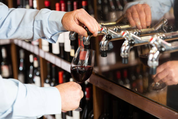 istock Hands of bartender pouring red wine from tap 1240206563