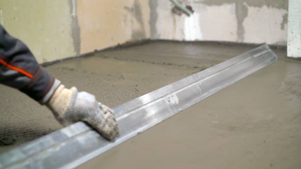 The worker levels the floors with a sinker. The construction technician is working by leveling the concrete floor to be smooth.