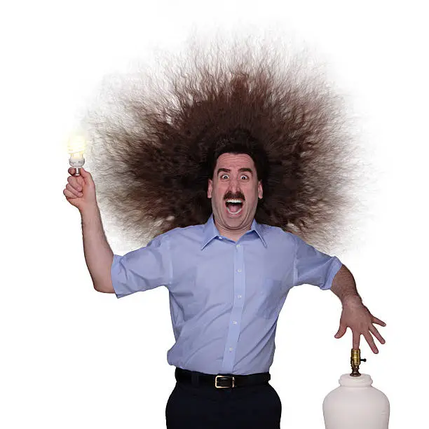 A man with long hair getting an electric shock while changing a lightbulb.