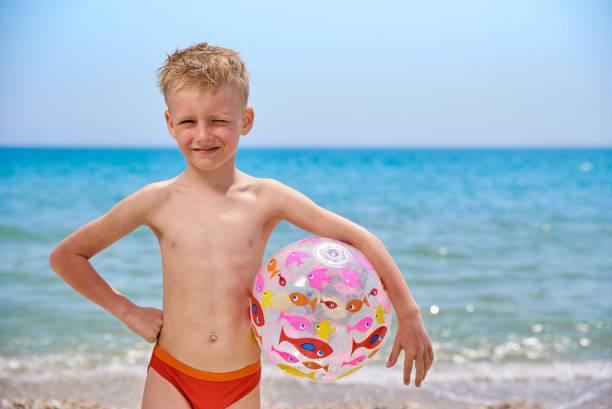 niño de 7 años con bola inflable en la playa cerca del mar - 6 7 years lifestyles nature horizontal fotografías e imágenes de stock