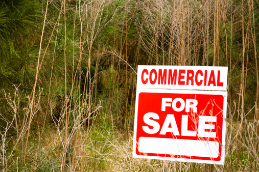 Commercial real estate sign on empty acreage. Land development for sale.