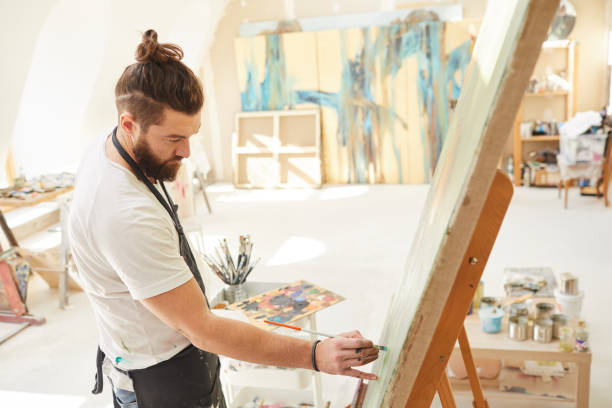 istock Bearded Artist Painting on Easel in Studio 1240227644
