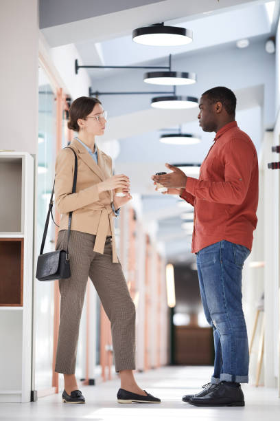 istock Two Young Business People Chatting in Office Hall 1240233139