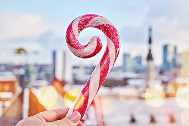 Photo of Striped candy cane lollipop in hand against old city of Tallinn