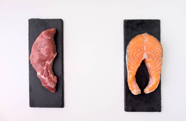 istock Choice: fish or meat. Salmon steak and pork steak on a white background 1240254092