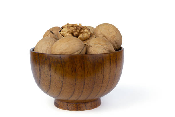 Walnuts in a brown wooden bowl, isolated on a white background. Front view