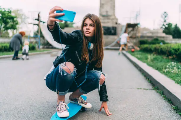 Photo of Girl taking selfie on skateboard