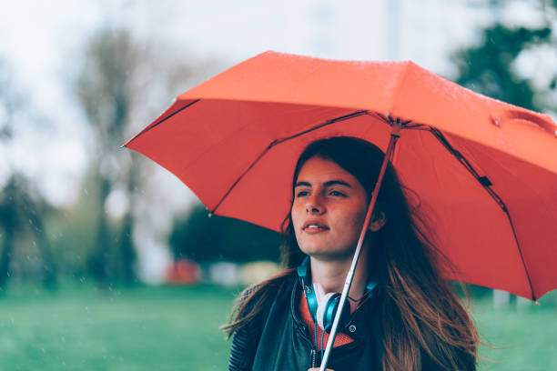 Dreamy girl hiding under umbrella