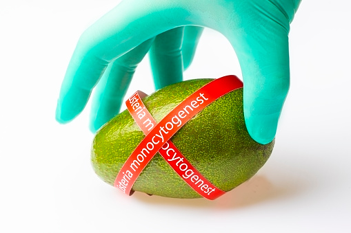 Ripe avocado entwined with ribbon with text Listeria monocytogenes . Consumer safety concept.