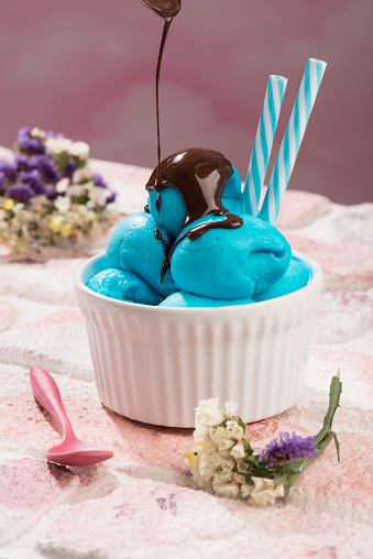 blue icecream is in the white cup plate on the pink background