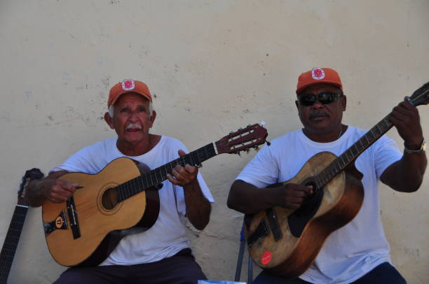 Santiago de Cuba street scenes So much of Cuban life takes place on the city streets: negotiating with ambulant vendors, gossiping and board games with neighbors, playing music for passersby, etc. Here members of a musical group called Jubilados del Caribe perform for passersby. Photos taken in Santiago de Cuba in January 2017. cuban ethnicity photos stock pictures, royalty-free photos & images