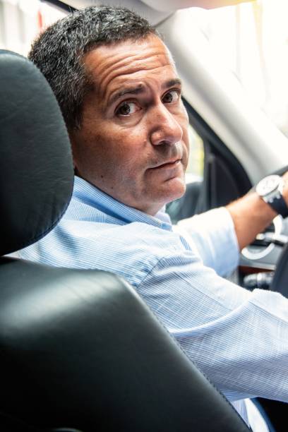 istock Mature man driving his car looking back 1240325662
