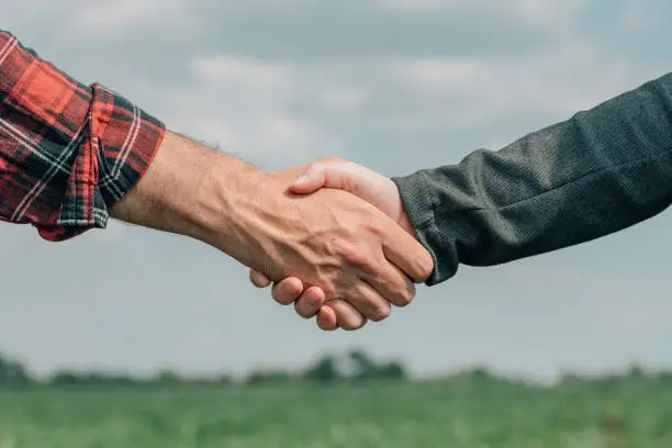 Photo of Mortgage loan officer and farmer shaking hands upon reaching an agreement