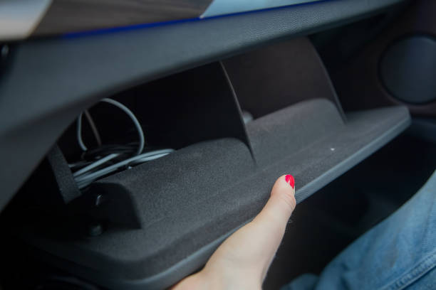 female hand opens a glove box in a black car interior. there are cables inside. close-up, soft focus. stock photo