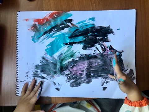 little boy paints on white sheet