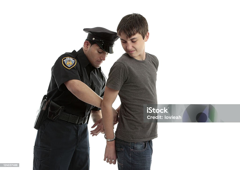 Policeman handcuffing teenager A police officer arrests and handcuffs a young male teen felon. Child Stock Photo