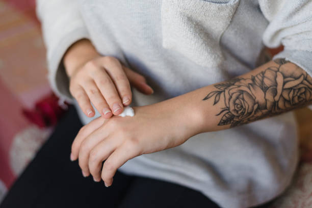 donna tatuata che le mette la crema sulla mano - arm tattoo foto e immagini stock