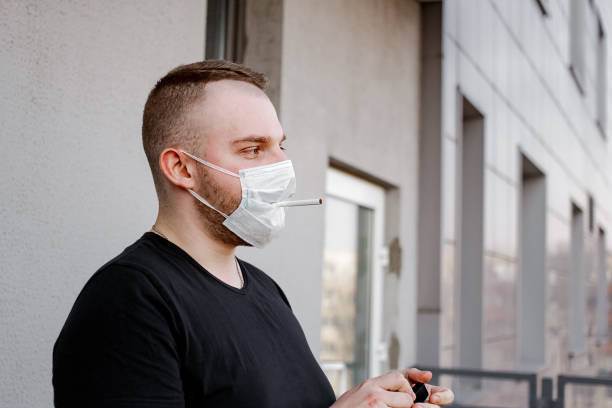 istock Guy with protective mask on the street smokes cigarette 1240394161
