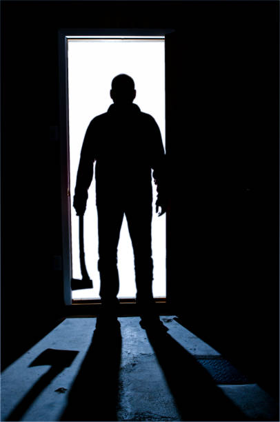 istock Shadow of man in door with an axe 1240404473