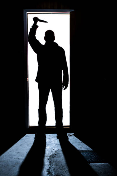 istock Shadow of man in door with knife 1240404982