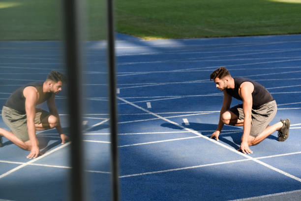 istock selective focus of handsome runner in start position on running track at stadium 1240469176
