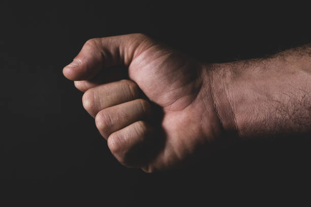 istock Arm with clenched fist on black background 1240474446