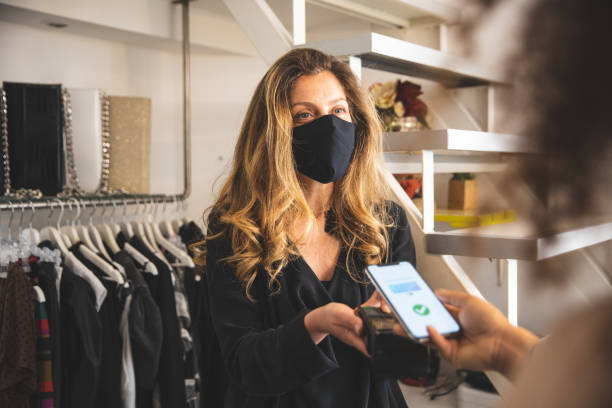 бесконтактная оплата во время пандемии covid-19 с использованием всей защиты безопасности - credit card paying boutique young women стоковые фото и изображения