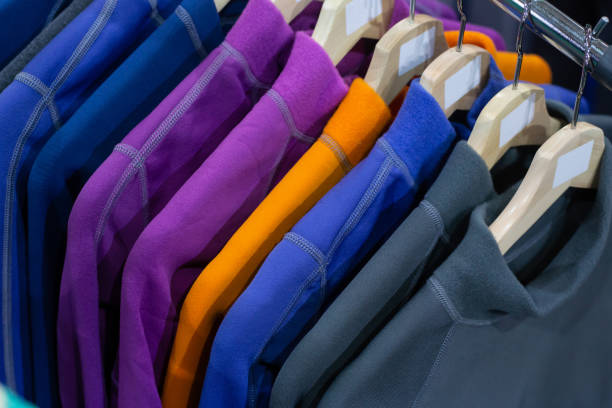 giacche in pile calde appese al rack nel negozio di sport - shirt hanger hanging blue foto e immagini stock