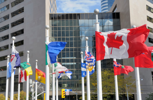 Flags of Canada's various provinces in downtown Toronto. Focus on Canadian flag.