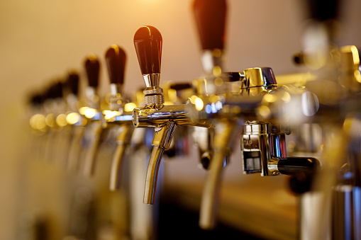 A row of beer taps in a bar.