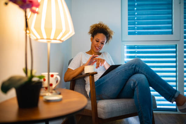 Beautiful Mixed Race Woman Reading a book on a digital tablet while using moisturizer