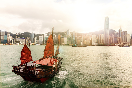 Traditional Chinese Junk ship sailing at Victoria Harbour to Hong Kong Island at sunset