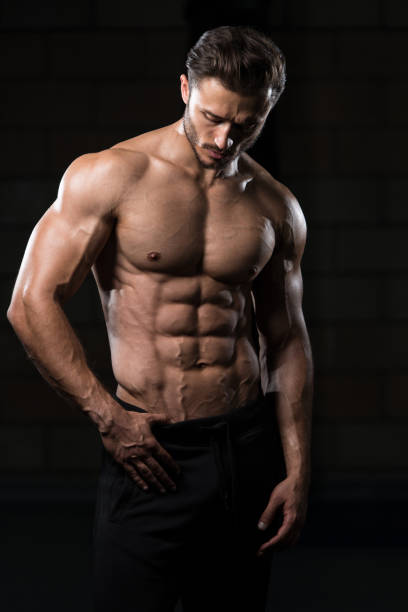 Muscular Man Flexing Muscles In Gym stock photo