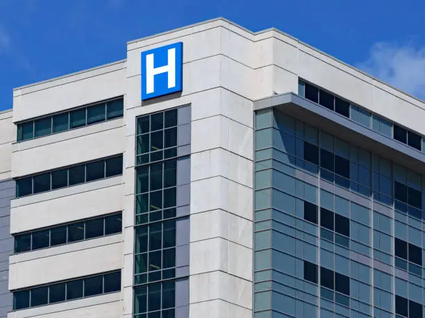Photo of large modern building with blue letter H sign for hospital