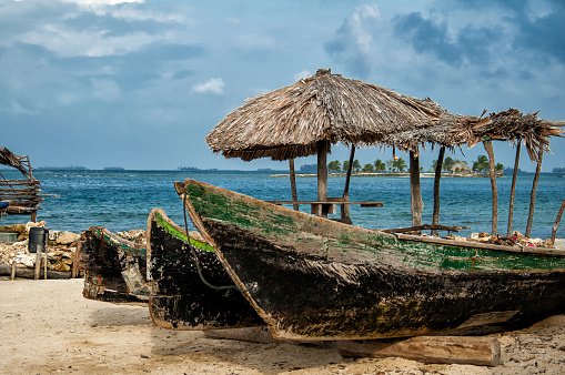 Rustic wooden canoes and palapa huts in the Cayos Cochinos islands of Honduras