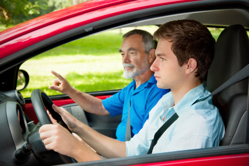 Teenager learning to drive with his driving instructor