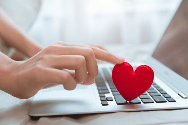 Hand touching red heart on laptop keyboard for flirt love chat or lover online text messenger for find date couple during stay home Coronavirus pandemic situation Hand touching red heart on laptop keyboard for flirt love chat or lover online text messenger for find date couple during stay home Coronavirus pandemic situation work romance stock pictures, royalty-free photos & images
