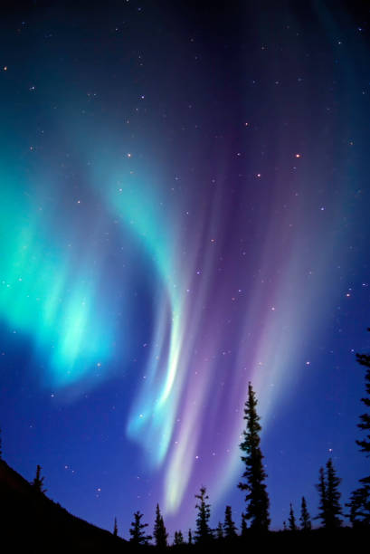 la aurora boreal es una pantalla de luz natural en el cielo particularmente en la alta latitud de las regiones árticas, causada por la colisión de partículas cargadas de energía con átomos en la atmósfera de gran altitud (termosfera). - magnetosphere fotografías e imágenes de stock