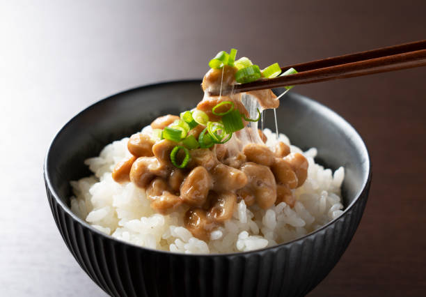 Natto and rice set against a dark wooden background Natto on rice set against a dark wooden background is lifted with chopsticks natto stock pictures, royalty-free photos & images