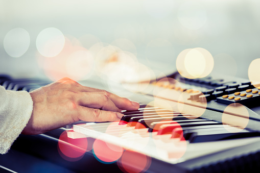 pianist hands playing piano with colorful twinkling bokeh. music background