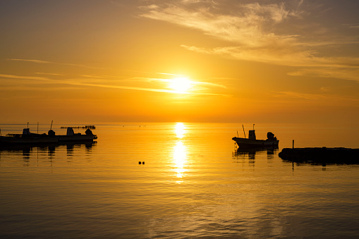 Silhouette Fisherman boats floating on the sea water over colorful sunrise red orange sunrise sky background, Bahrain.